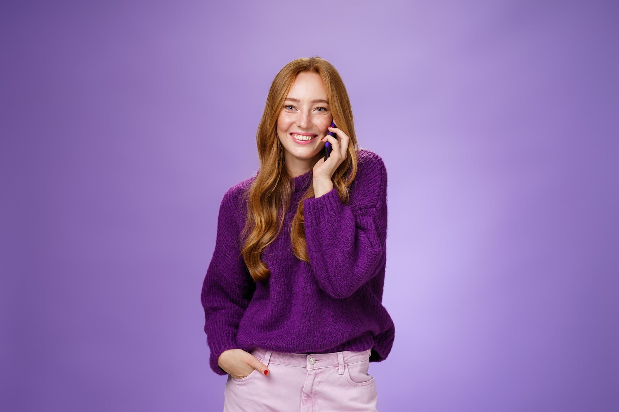 Smiling woman on a phone call wearing a purple sweater