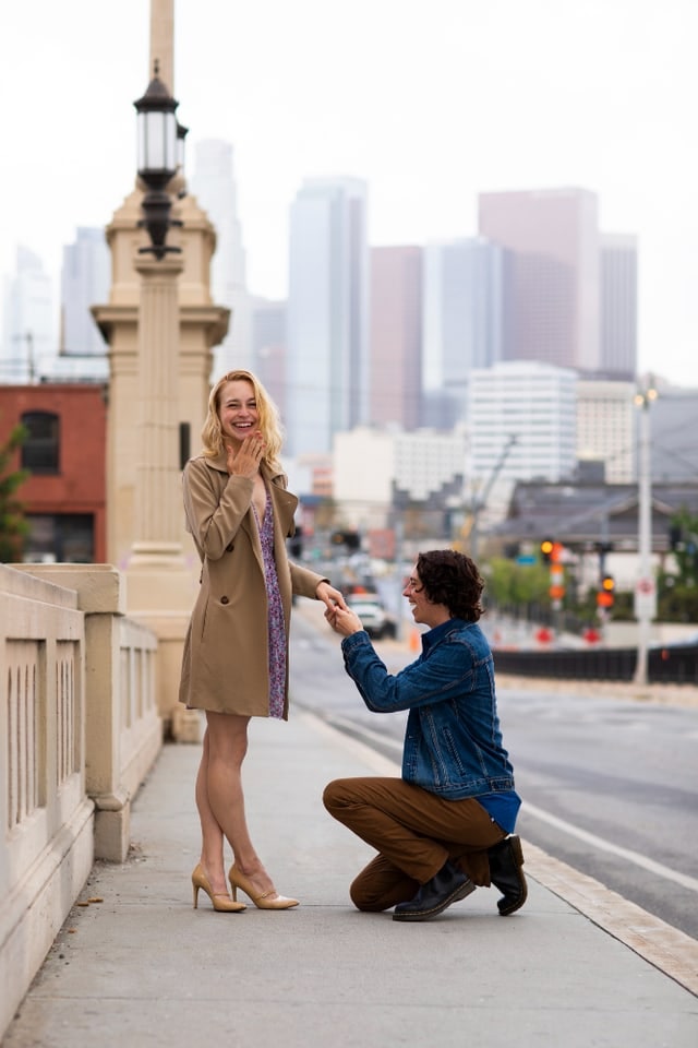 Couple sharing a proposal moment on a city bridge