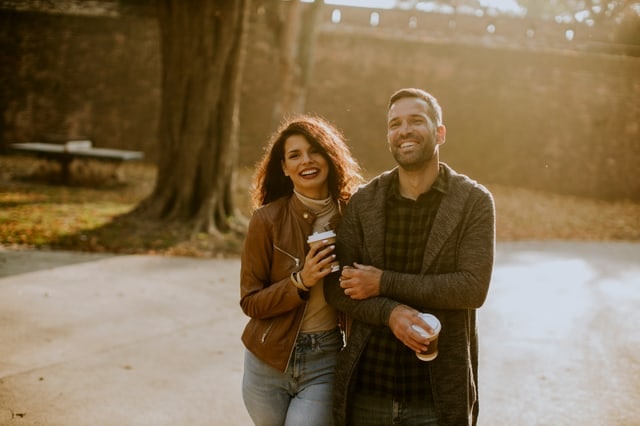 Couple walking outdoors with coffee cups