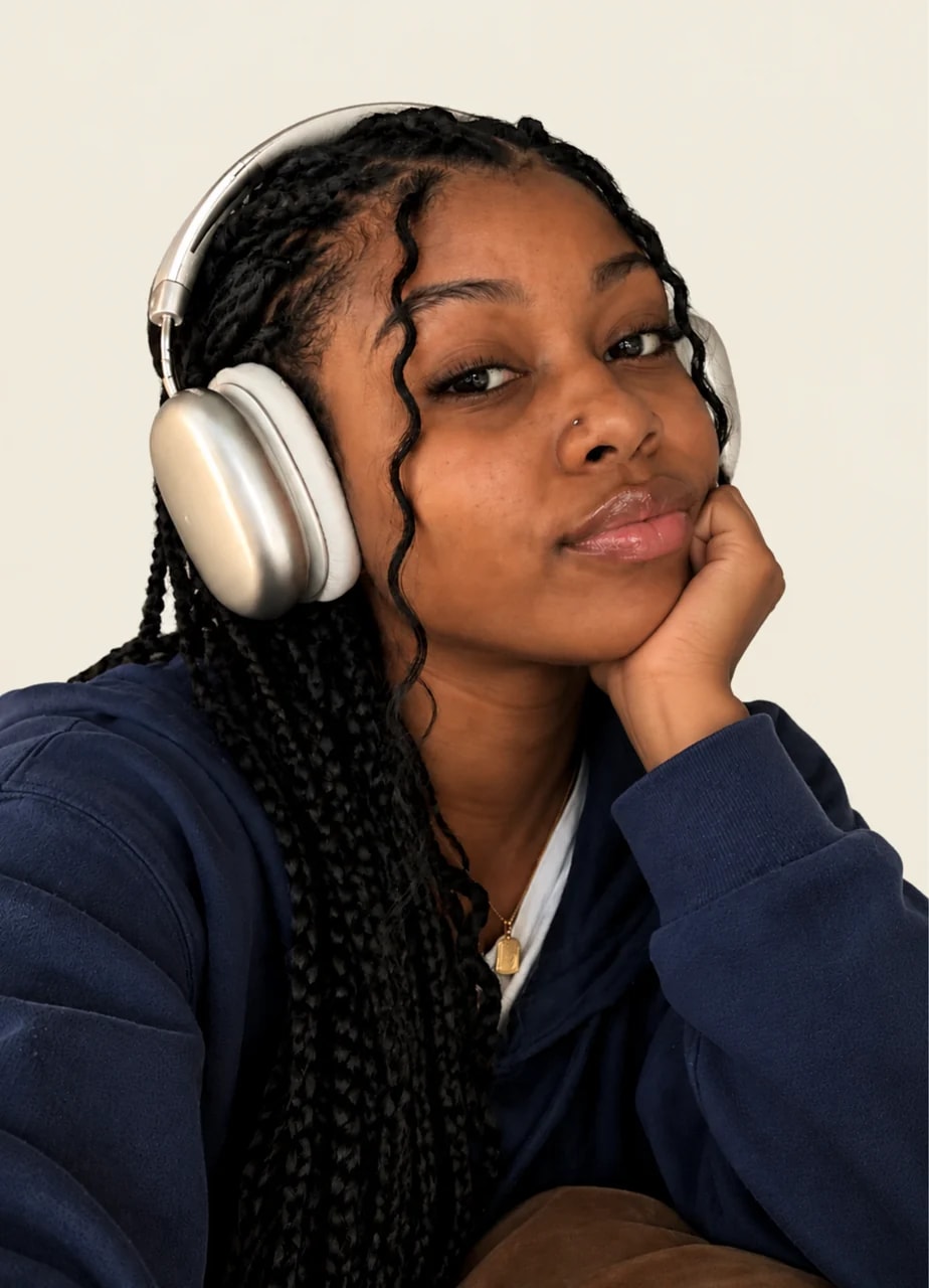 Young woman in silver headphones and a navy hoodie resting her chin on her hand