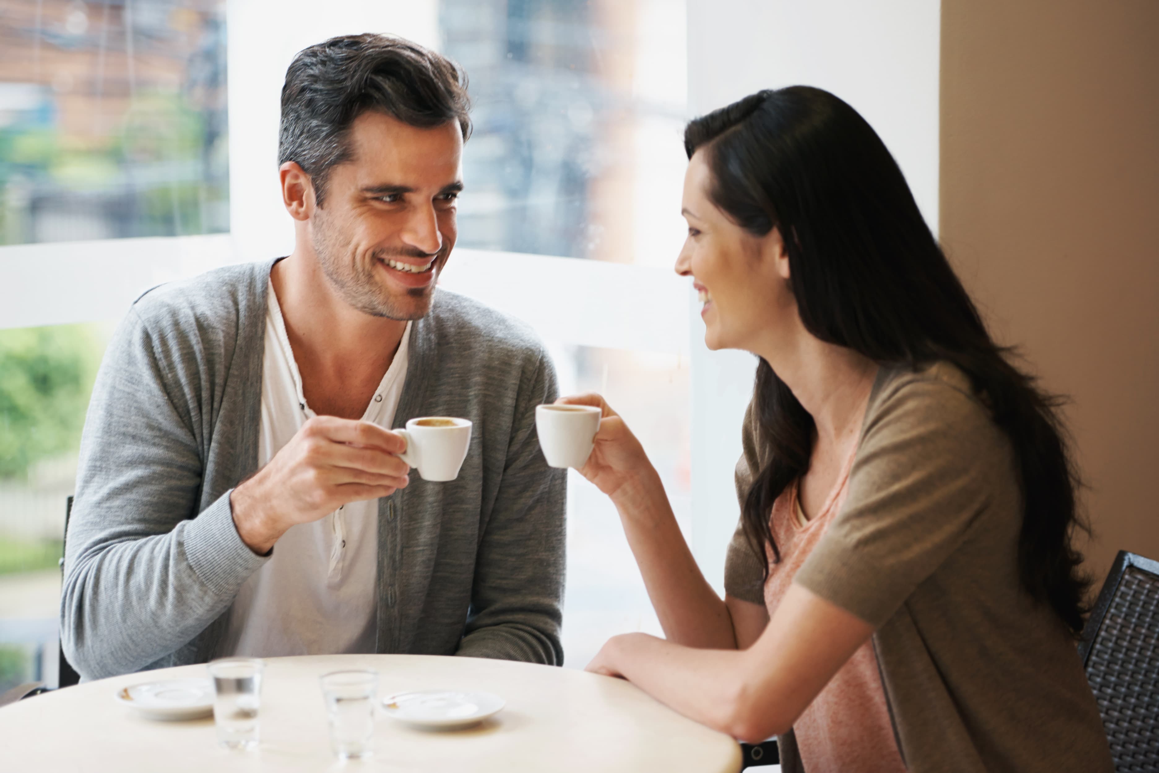 A couple smiling while sharing coffee at a cafe table